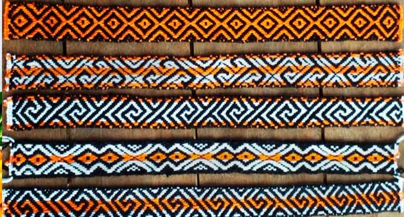 Five woven beaded bands in orange, black and white kene patterns, laid side by side